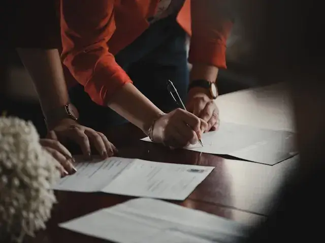 dos personas la cual una de ellas se encuentra revisando un documento para luego firmarlo.